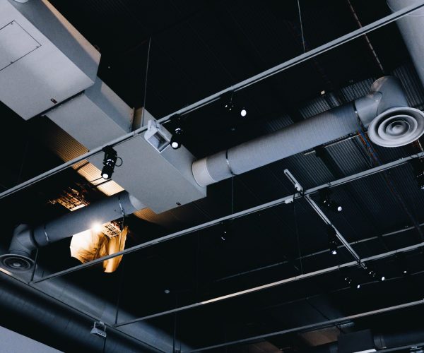 A low angle shot of a metal black ceiling with white ventilation pipes